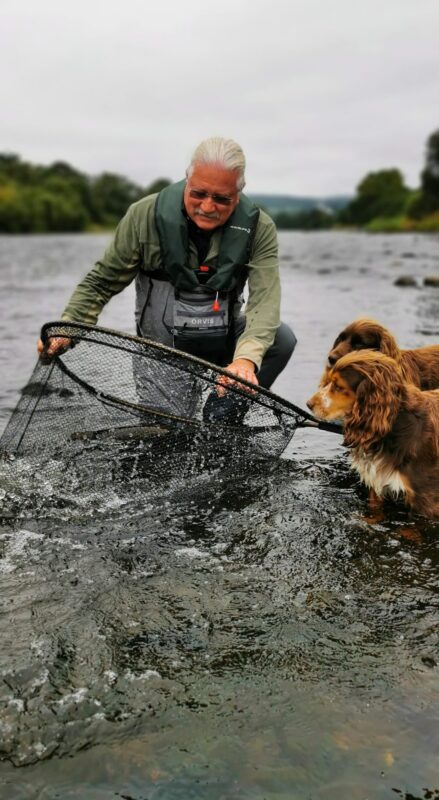 Dave Bowden with a fish in the net accompanied by his two Ghillies